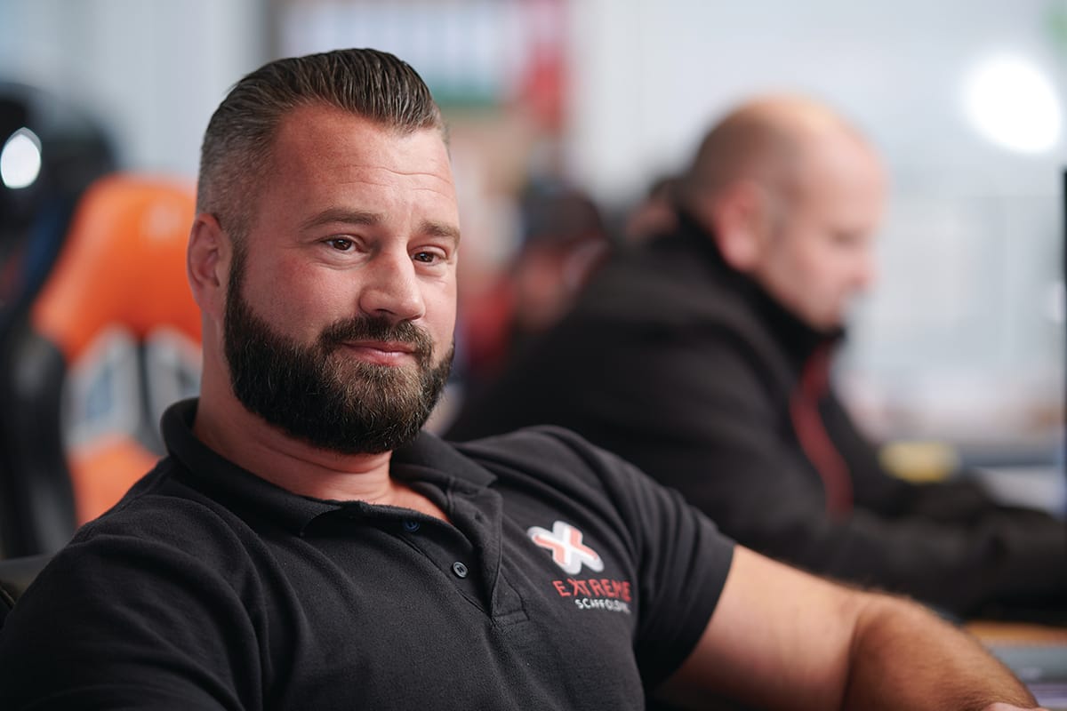 Bearded man in black polo at office desk