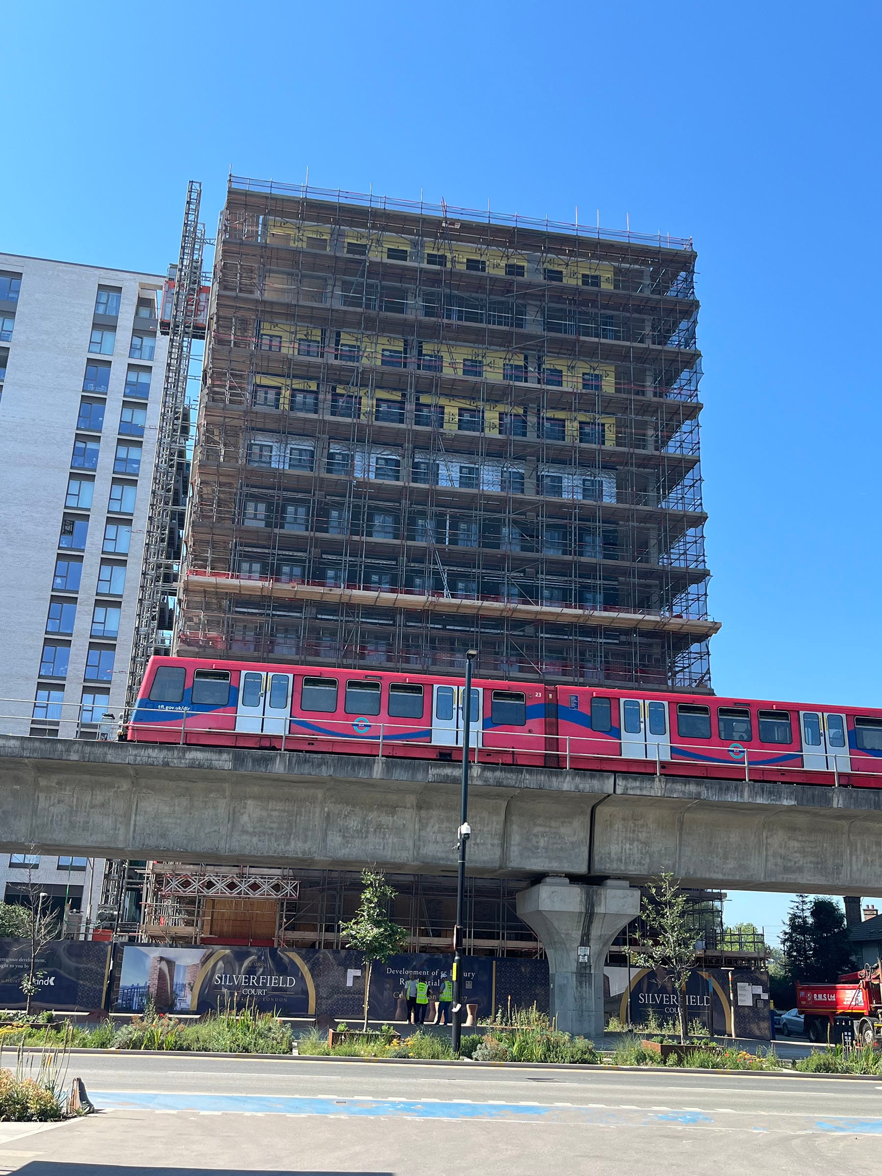 DLR train passing scaffolded building under construction