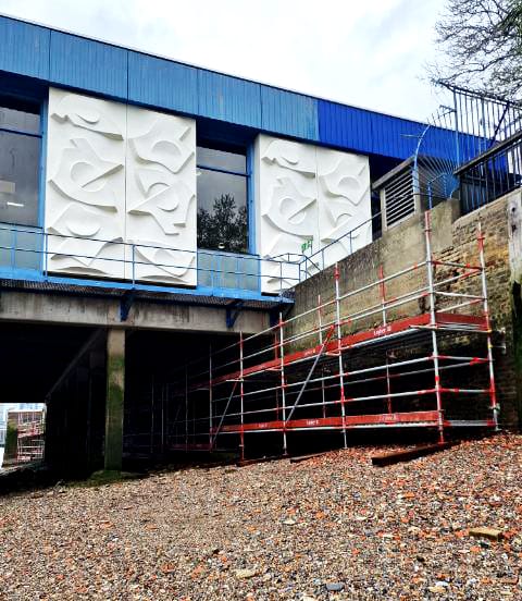 Building exterior with white panels and scaffolding
